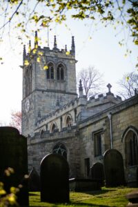 Historic gothic-style church with towering steeple and ancient graveyard, capturing serene atmosphere.