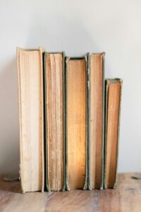 A collection of vintage books lined up on a wooden table, exuding a cozy aesthetic.
